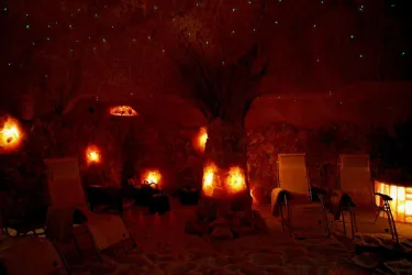 Ein entspannender Raum mit Salzsteinwänden und warmem, sanftem Licht. Liegestühle laden zur Erholung ein.