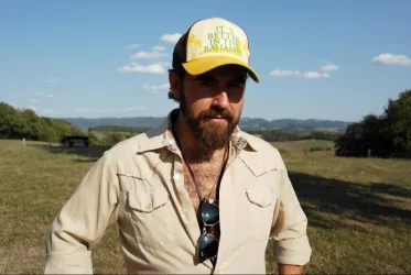 Ein Musiker steht im Dunkeln und spielt Gitarre. Ein helles Licht strahlt von hinten und schafft eine stimmungsvolle Atmosphäre.