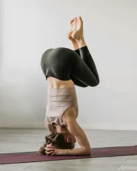 Zwei Frauen praktizieren Yoga in einem hellen Raum mit Ziegelsteinen und Pflanzen. Der Text auf dem Bild kündigt eine Yoga-Veranstaltung an.