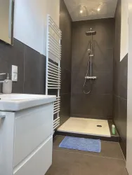 Ein Tageslichtbad mit einer großen Dusche und einem modernen Waschtisch und reichlich Stauflächen.