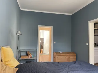 Vom stilvoll eingerichteten Schlafzimmer mit blauen Wänden und einem gemütlichen Bett geht es in das Schrank- und weiter in das Badezimmer