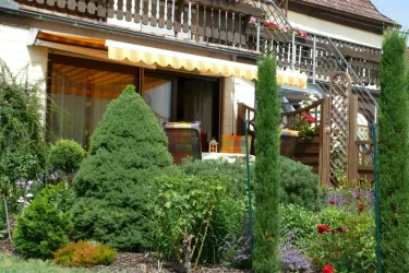 Ein schöner Garten mit grünen Sträuchern und bunten Blumen. Auf der Terrasse mit Markise. Gemütlicher Platz zum Sonnenbaden, oder gemütlicher Trollschoppen.