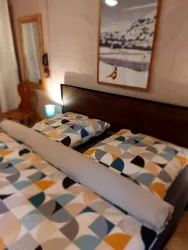 Ein gemütliches Schlafzimmer mit einem großen Bett und bunten Kissen. An der Wand hängt ein Bild von einer winterlichen Landschaft.