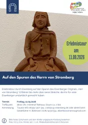 Eine Holzfigur eines Mannes, die in traditioneller Kleidung dargestellt ist. Der Hintergrund enthält Informationen zu einer Veranstaltung in Eisenberg.