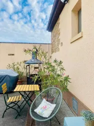 Ein kleiner Außenbereich mit einem runden Stuhl und einem Tisch. Umgeben von Pflanzen und einem Pavillon ist der Platz einladend und gemütlich.