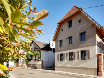 Ein modernes Haus an einer ruhigen Straße. Bunte Pflanzen rahmen die Szene ein.
