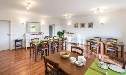 Ein helles Esszimmer mit Holztischen und Stühlen. Es gibt dekorierte Tische und einen harmonischen, einladenden Raum.