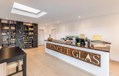 Ein moderner Weingut mit einem einladenden Empfangstresen. Regale sind mit verschiedenen Weinen gefüllt und die Atmosphäre ist hell und freundlich.