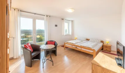 Ein helles Schlafzimmer mit zwei Einzelbetten und einem kleinen Tisch. Große Fenster bieten einen schönen Ausblick.