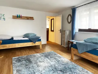 Ein helles Zimmer mit zwei Einzelbetten, mit Zugang zum Flur.