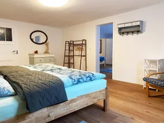 Schlafzimmer mit großem Doppelbett und direkten Zugang zu Schlafzimmer 2 und zum Bad.