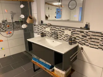 Ein modernes Bad mit großzügigem Waschtisch und ebenerdiger Dusche.