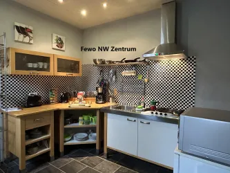 Eine moderne Küche mit schwarz-weißem Fliesenmuster und Holzschränken. Die Küchenzeile ist gut ausgestattet und funktional gestaltet.