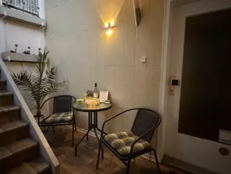 Ein gemütlicher Eingangsbereich mit einem kleinen Tisch und zwei Stühlen. Eine Pflanze und eine Flasche auf dem Tisch sorgen für eine einladende Atmosphäre.