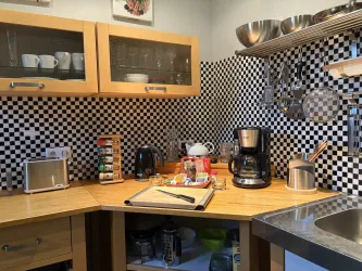 Eine moderne Küche mit einem schwarzen und weißen Schachbrettmuster an der Wand. Auf der Arbeitsfläche stehen verschiedene Küchengeräte und Utensilien.