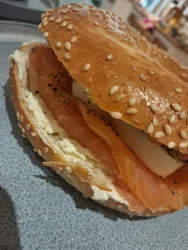 Ein frisch zubereiteter Bagel mit Sesamkruste, gefüllt mit Frischkäse und Räucherlachs. Das Gericht hat eine appetitliche Ausstrahlung und eignet sich gut für ein Frühstück.