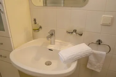 Ein modernes Waschbecken in einem stilvollen Badezimmer. Es gibt Handtücher und Pflegeprodukte auf dem Regal.