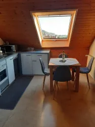 Eine gemütliche Küche mit einer Essecke und einem großen Fenster. Der Raum hat Holzwände und ist gut beleuchtet.