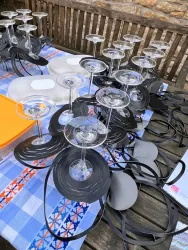 Eine Sammlung von Gläsern mit schwarzen Untersetzern auf einem Tisch. Der Tisch ist mit einer karierten Tischdecke bedeckt.