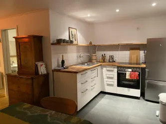 Eine moderne Küche mit Holzregalen und eleganten Küchengeräten. Der Raum ist hell erleuchtet und verfügt über einen gemütlichen Esstisch.