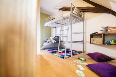 Ein gemütliches Kinderzimmer mit einem Etagenbett und buntem Teppich.