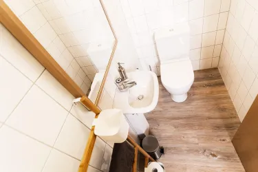 Ein modernes Badezimmer mit Toiletten und Waschbecken. Der Boden ist mit Holzfurnier ausgelegt und die Wände sind gefliest.