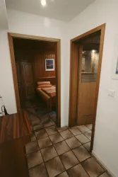 Ein Flur mit zwei Türen, der zu einem Schlafzimmer und einem Badezimmer führt. Die Wände sind in warmen Tönen gehalten, und der Boden ist mit Fliesen ausgelegt.