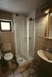Ein einfaches Badezimmer mit Dusche, Toilette und Waschbecken. Die Wände sind gefliest und das Licht ist angenehm.