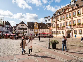 Ein schöner Platz mit historischen Gebäuden und bunten Fassaden. Paare und Menschen genießen einen sonnigen Tag im Freien.
