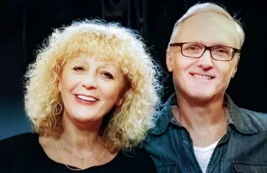 Ein lächelndes Paar steht freundlich nahe beieinander. Beide wirken glücklich und entspannt.