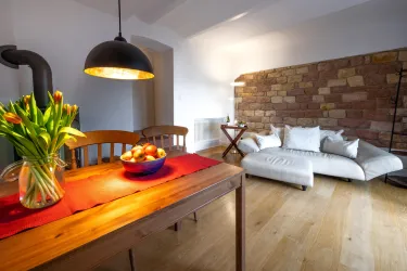 Eine gemütliche Wohnung mit einem Holztisch und einem Sesselsessel. Auf dem Tisch steht eine Vase mit Tulpen und eine Schüssel mit Äpfeln.