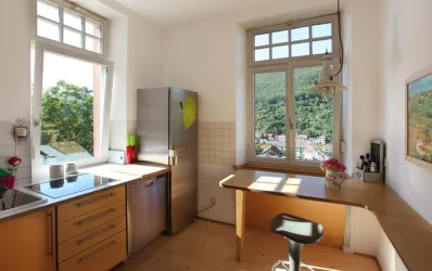 Eine helle Küche mit modernen Möbeln und großen Fenstern. Durch die Fenster ist eine schöne Aussicht auf die umliegende Natur zu sehen.