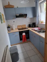 Eine moderne Küche mit blauen Schränken und Holzarbeitsfläche. Sie ist gut ausgestattet mit Geräten und einem kleinen Tisch.