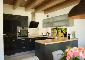 Eine moderne Küche mit schwarzem Schrankdesign und Holzarbeitsfläche. Helle Farben und viel Licht schaffen eine einladende Atmosphäre.