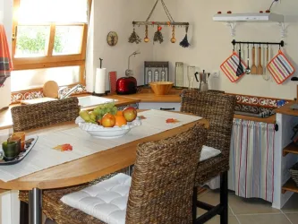 Eine gemütliche Küche mit Barhockern an einem Holztisch. Auf dem Tisch steht eine Obstschale  für die Gäste.