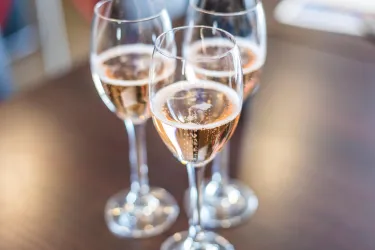 Drei Gläser mit Roséwein stehen auf einem Tisch. Die Gläser sind elegant und reflektieren das Licht.