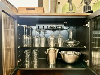 Ein gut sortierter Küchenschrank mit Gläsern, einer Karaffe und einem Eiskübel. Der Schrank ist modern und ordentlich.