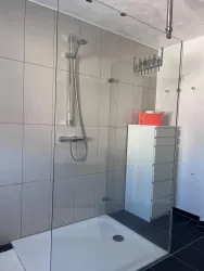 Eine moderne Dusche mit Glasabtrennung und regenduschähnlichem Duschkopf.