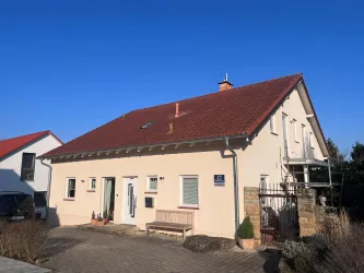 Ein modernes Wohnhaus mit einladendem Eingang mit einer Bank und Pflanzen.