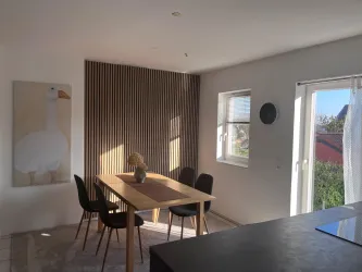 Ein moderner, heller Essbereich mit Stühlen und einem Tisch.