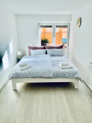 Ein gemütliches Schlafzimmer mit einem großen Bett und frischen Handtüchern. Helle Wände und viel natürliches Licht schaffen eine einladende Atmosphäre.