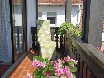 Der Balkon von Zimmer 1 mit Liegestuhl und Blumenschmuck lädt nach einem Ausflug an der Deutschen Weinstraße zum Entspannen ein.