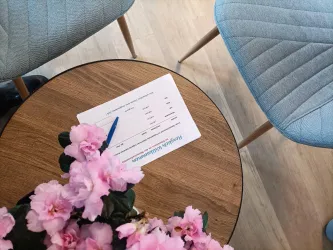 In Zimmer 2 empfängt die Gäste eine Willkommenskarte an der Sitzecke mit rundem Holztisch und blauen Stühlen.