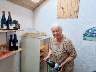Gründerin Marianne Ehmer am Getränkekühlschrank des Gästehauses an der Weinstraßenmitte. Für Gäste stehen Getränke und Weine aus der Pfalz bereit.