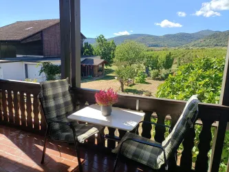 Der Balkon von Zimmer 5 mit Sitzplätzen für zwei und Blick auf Weinberge und Pfälzerwald – ein Logenplatz an der Deutschen Weinstraße.
