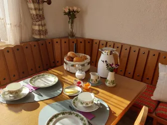 Liebevoll gedeckter Frühstückstisch im Gästehaus an der Weinstraßenmitte: frische Brötchen, Kaffee und Porzellan mit Weinlaubmotiv in gemütlicher Pfälzer Atmosphäre.