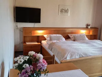 Zimmer 4 mit großem Doppelbett, Leselicht im Kopfteil und Flachbildfernseher.