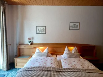 Zimmer 3 ist ein klassisch eingerichtetes Doppelzimmer im Gästehaus an der Weinstraßenmitte in Neustadt-Diedesfeld – mit Holzmöbeln, Holzdecke, beleuchtetem Bettkopfteil und Balkonzugang.
