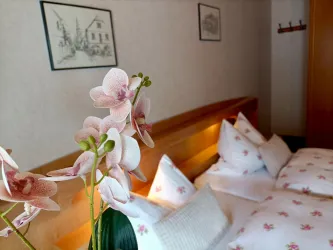 Liebevolle Details in Zimmer 3: Eine Orchidee und warmes Licht am Bettkopfteil sorgen für eine gemütliche Atmosphäre.