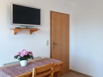 In Zimmer 1 gehören ein Flachbildfernseher und ein kleiner Tisch mit Stuhl zur Ausstattung des Einzelzimmers.